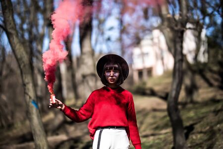 Beautiful woman in a leather jacket and sunglasses in red smokeの写真素材