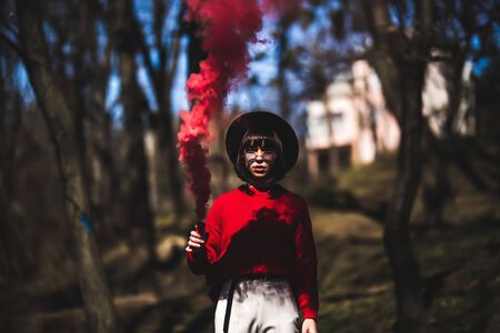 Beautiful woman in a leather jacket and sunglasses in red smokeの写真素材