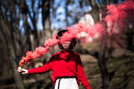 Beautiful woman in a leather jacket and sunglasses in red smokeの写真素材