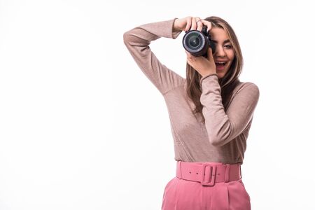 Attractive brunette aims her camera. composing a photograph in studio, isolated on white