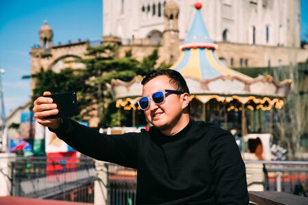 Happy guy making selfie portrait with smartphone in Tibidabo, Barcelona, Spain.の写真素材
