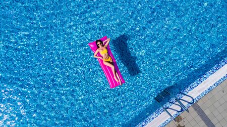 Slim young woman lying on air mattress in the poolの写真素材