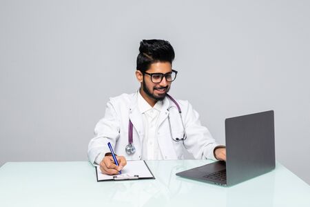 Attractive male physician writes a prescription on desk over blue backgroundの写真素材
