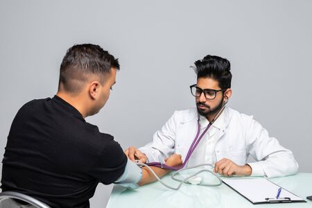 Doctor Holding Dial While Measuring Man's Blood Pressure