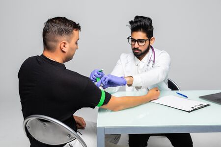Close-up of young doctor in white coat injecting the patient's hand at the table at hospitalの写真素材