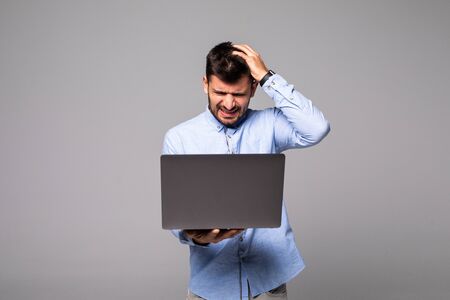 Smiling cheerful young man holding laptop and typing.