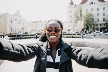 Young african woman take selfie on the sunny city street