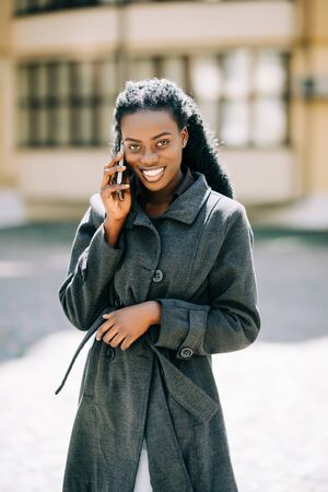 Portrait of pretty black woman in urban background talking on phoneの写真素材