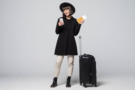 Young woman with travel suitcase, passport standing smartphone mobile phone in hand on white backgroundの写真素材