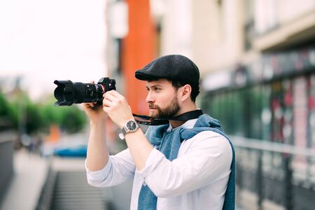 Young man with camera photographing at streetの写真素材