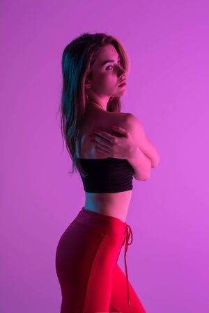 Young woman possing while standing isolated on pink light backgroundの写真素材