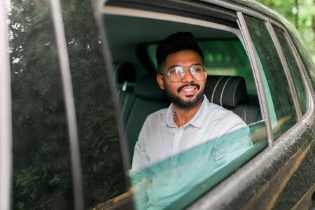 Handsome businessman talking on the mobile phone while sitting on back seat of a car. Caucasian male business executive travelling by a car and making phone call.の写真素材