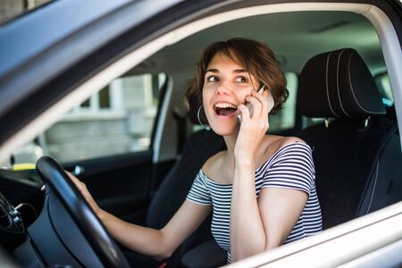 Driver woman driving a car distracted on the phone and looking at side