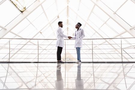Full body portrait of two medical people handshaking, isolated on white backgroundの写真素材