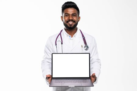 Full length of a medical doctor standing in the studio while working with laptop, isolated on white backgroundの写真素材