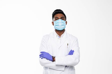 Handsome Indian Male Doctor with surgical or safety health Mask on. standing isolated over blue backgroundの写真素材