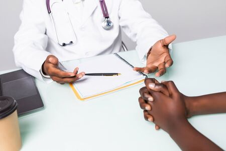 Close up of Indian man doctor have a consultation with depressed african female patient in clinic