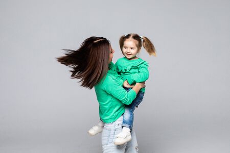 smiling mother holding happy daughter on hands, isolated on whiteの写真素材