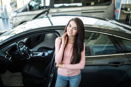 Beautiful young woman buys a car in the dealership saloon.の写真素材