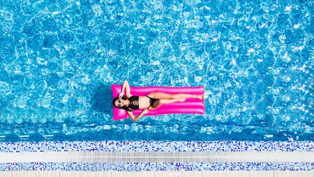 Slim young woman lying on air mattress in the poolの写真素材