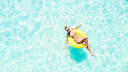Beautiful young woman in swimming pool aerial top view from above.の写真素材