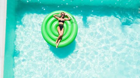 Young Girl relaxing on inflatable mattress in the pool. Summer vacations.の写真素材