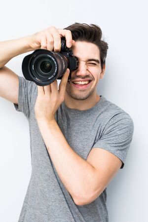 Young man posing with a photographic camera isolated on a gray backgroundの写真素材