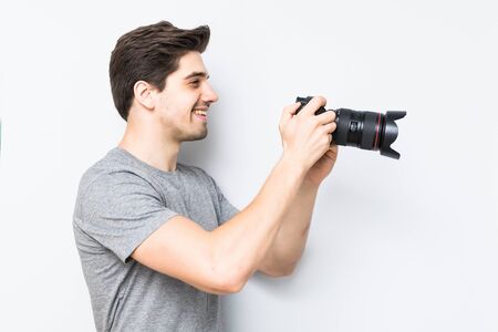 Young man posing with a photographic camera isolated on a gray backgroundの写真素材