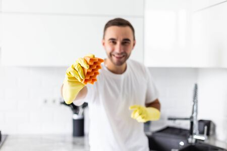 Happy young man in plaid shirt standing and washing dishes on the kitchenの写真素材