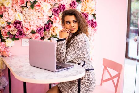 Beautiful woman working on laptop and smiling while sitting outdoorsの写真素材