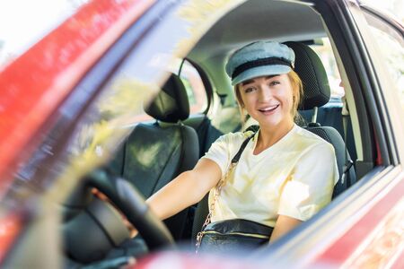 Happy woman driver behind the wheel red car