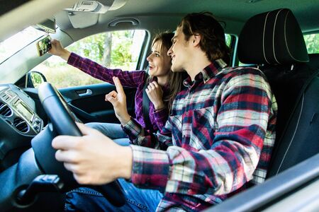 Happy young couple taking selfie in car