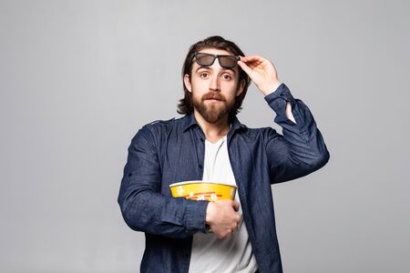 Man wearing a pair of 3D glasses and eating popcorn isolated on white background