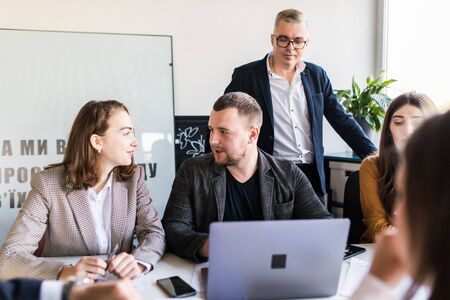 Group of happy diverse male and female business people in formal gathered around laptop computer in...