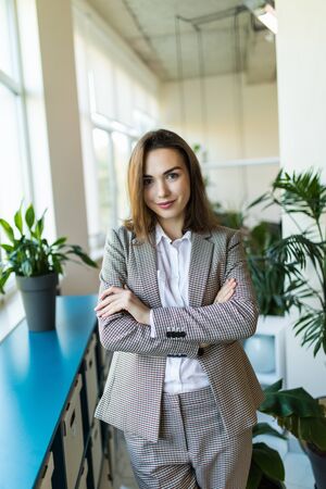 Portrait of a cute young business woman smiling, in an office environmentの写真素材