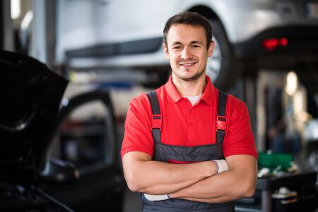 Portrait of a young beautiful car mechanic in a car workshop, in the background of service. Concept:...