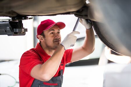 Portrait of a mechanic repairing a lifted car