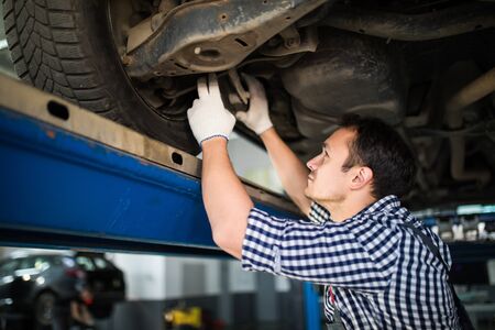 Portrait of mechanic repairing a lifted car