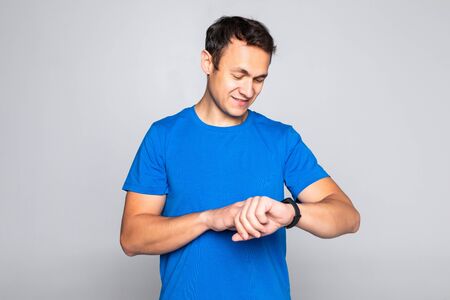Photo of stylish handsome young sportsman isolated on white background. Man using his smart watch