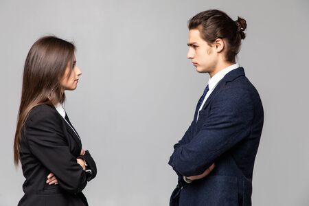 Concept of confrontation in business. Close up photo of two young serious confident people standing...