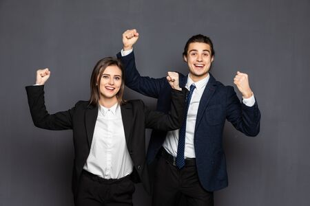 Young business woman and man showing winner gesture over gray backgroundの写真素材