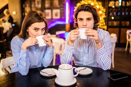 Portrait of affectionate couple in stylish clothes having coffee in cafeの写真素材