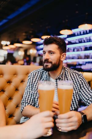 Two cheerful young men drinking beer in bar
