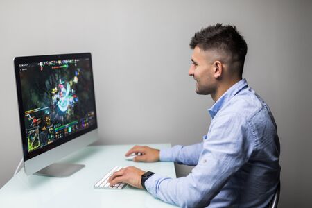 Young computer man gamer concentrating on his game at computer monitor with computer gameの写真素材