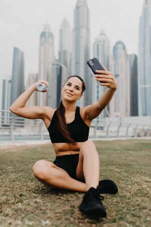 Young sport woman make selfie on the phone while sitting and relax on skyscrapersの写真素材