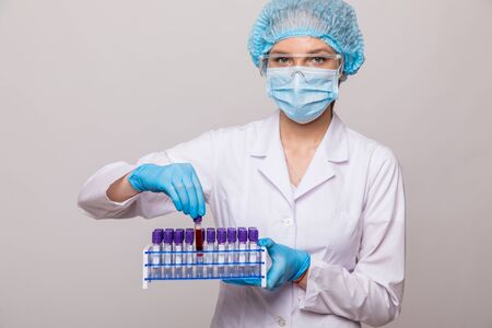 Close up doctor hands with blood testing tube isolated on gray backgroundの写真素材