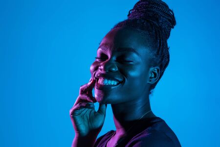 Portrait of young african woman possing in neon light background.の写真素材