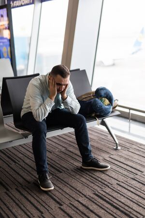 Depressed traveler waiting at airport after flights delays and cancellationsの写真素材