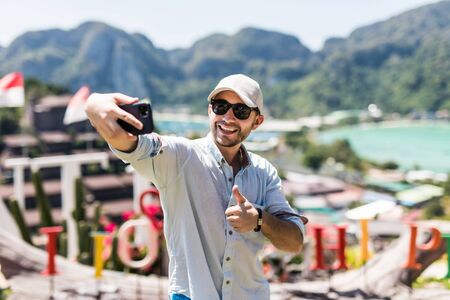 Handsome young man take selfie on the phone enjoying the view in phi phi island view point.