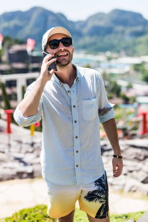 Handsome young man talking on the phone view in phi phi island view point.の写真素材